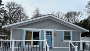 Una casa a due piani con facciata grigia, persiane blu e un portico anteriore bianco con ringhiera.