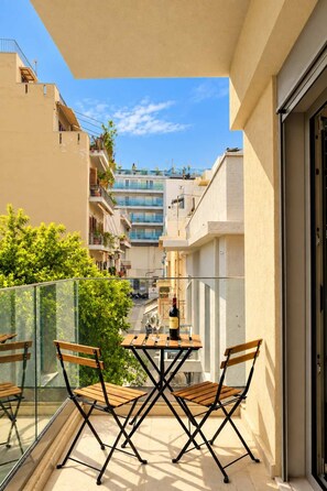 A balcony with a table and chairs, overlooking a residential street with buildings. - Irakleio Notos Boutique Apartments 1 (Iraklio)