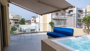 A rooftop terrace with a hot tub, a blue sofa, and a table with chairs. - Irakleio Notos Boutique Aprtments 3Private Jacuzzi (Iraklio)