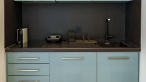 A compact kitchen with light blue cabinets, a black countertop, and a built-in sink. - Irakleio Notos Boutique Aprtments 3Private Jacuzzi (Iraklio)