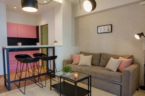 A modern living space with a kitchen, a sofa, and a coffee table. - Irakleio Notos Boutique Apartments 2 (Iraklio)