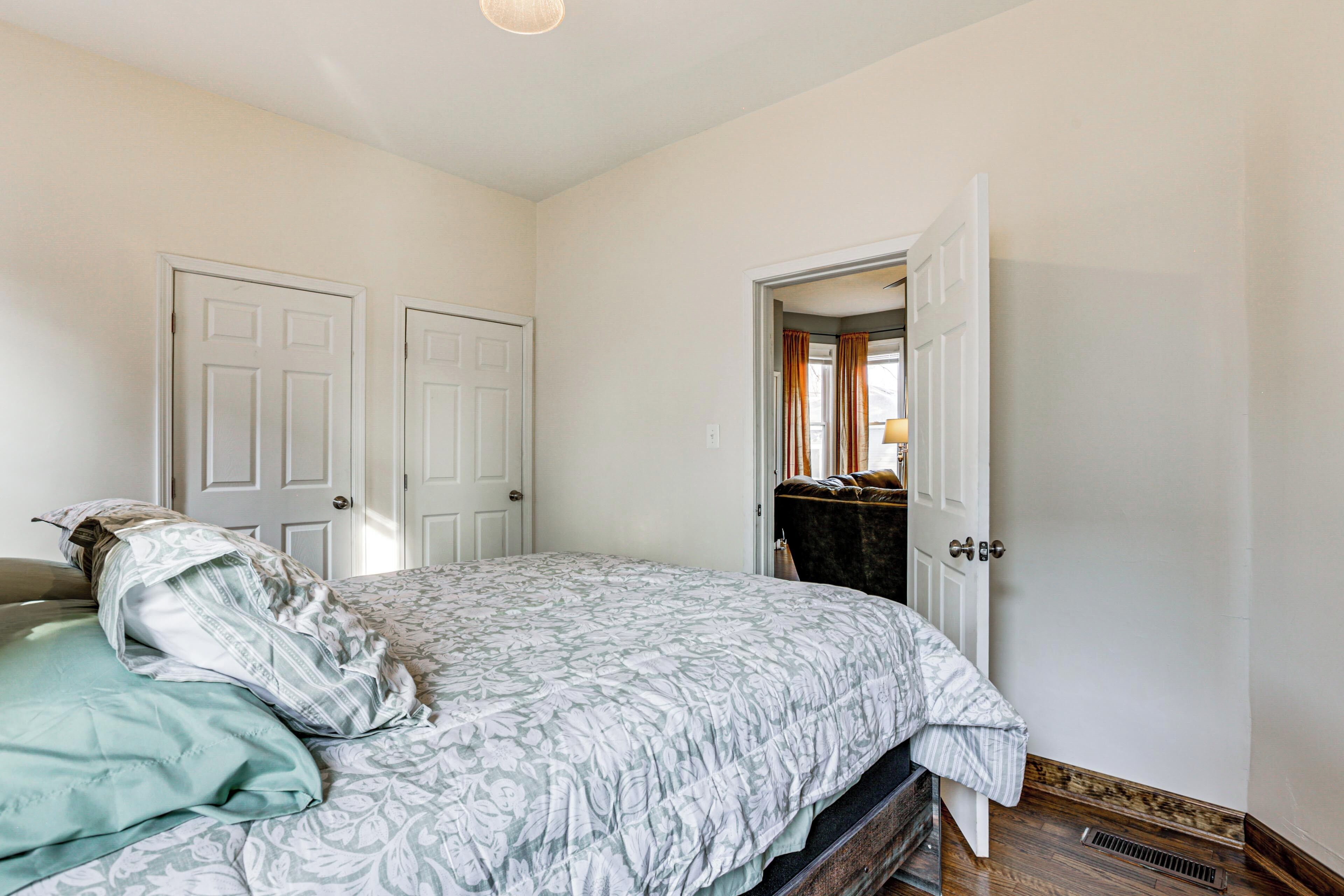 A bedroom with a bed, two doors, and a dresser.