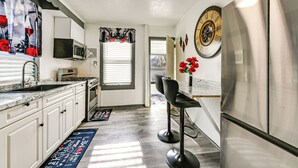 A modern kitchen with white cabinets, stainless steel appliances, and a bar stool. - Walk to Shops, Parks & Restaurants: Teaneck Escape (Teaneck)