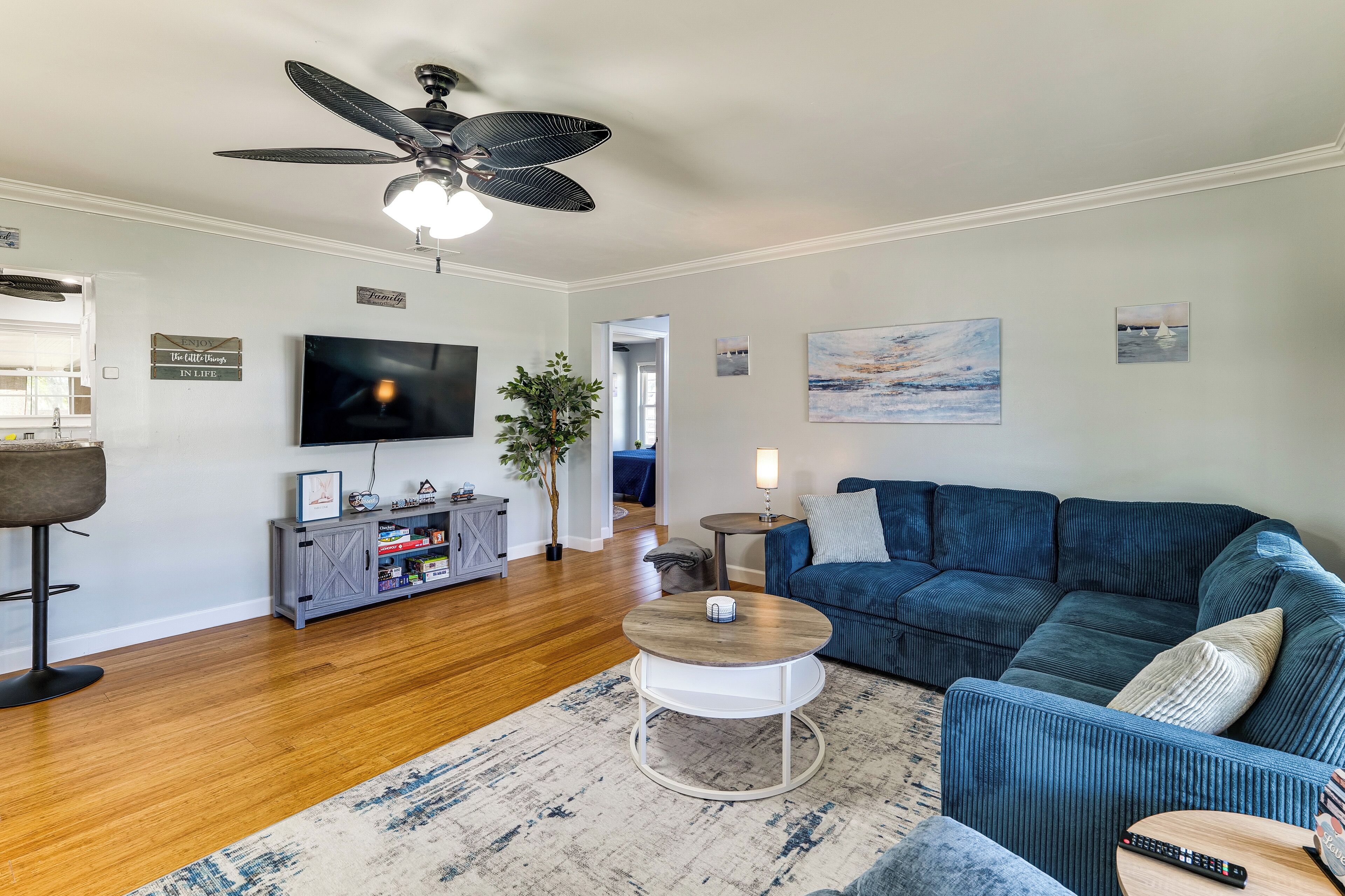 A living room with a blue sofa, a coffee table, a TV, and a ceiling fan.