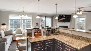 A modern kitchen with granite countertops, dark cabinetry, and a large island. There is a dining area with a sofa and chairs, and a fireplace. - 5 Mi to Sesquicentennial State Park: Quiet Home (Columbia)
