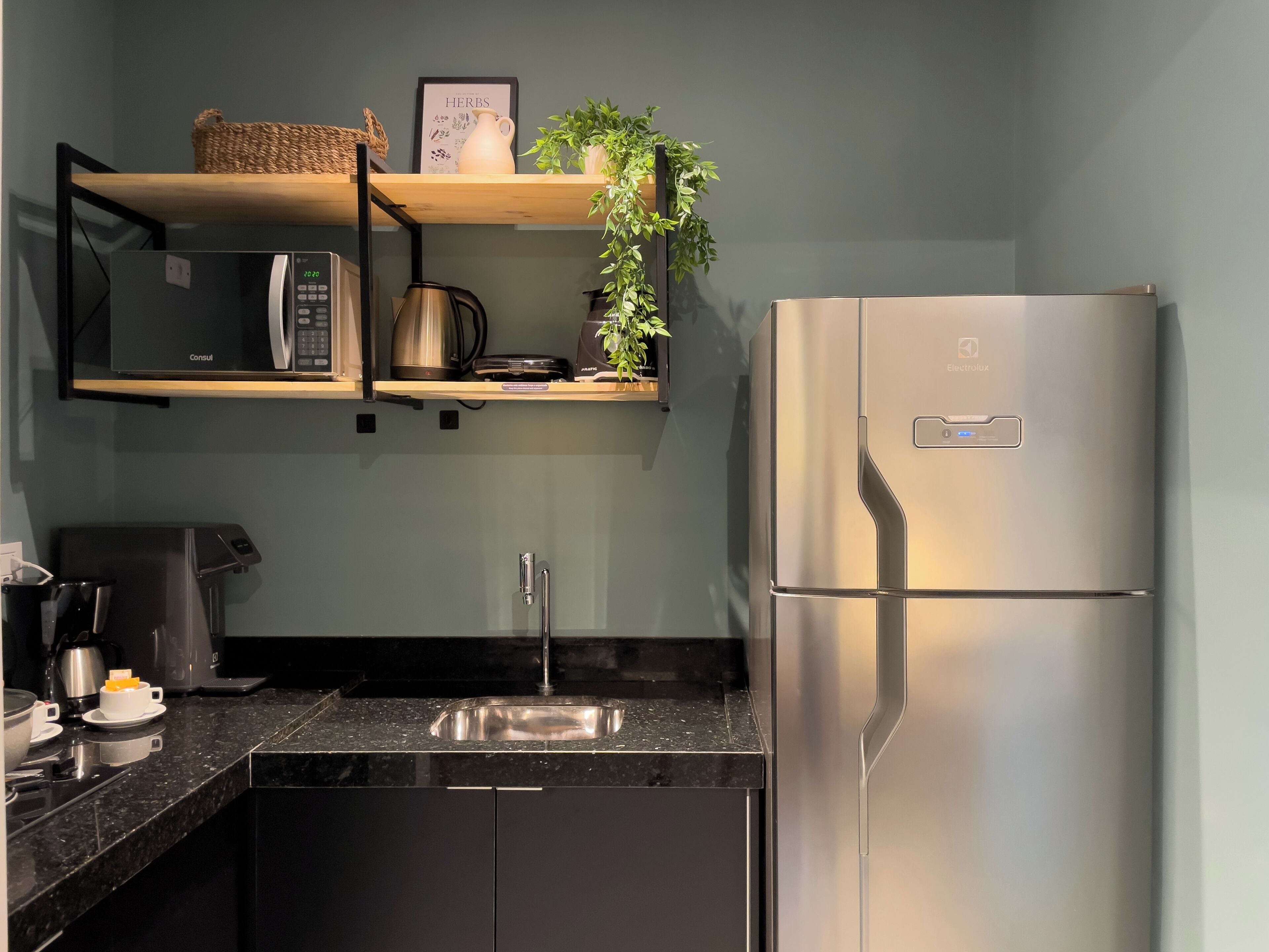 Een moderne keuken met een roestvrijstalen koelkast, een koffiezetapparaat, een waterkoker en een spoelbak.