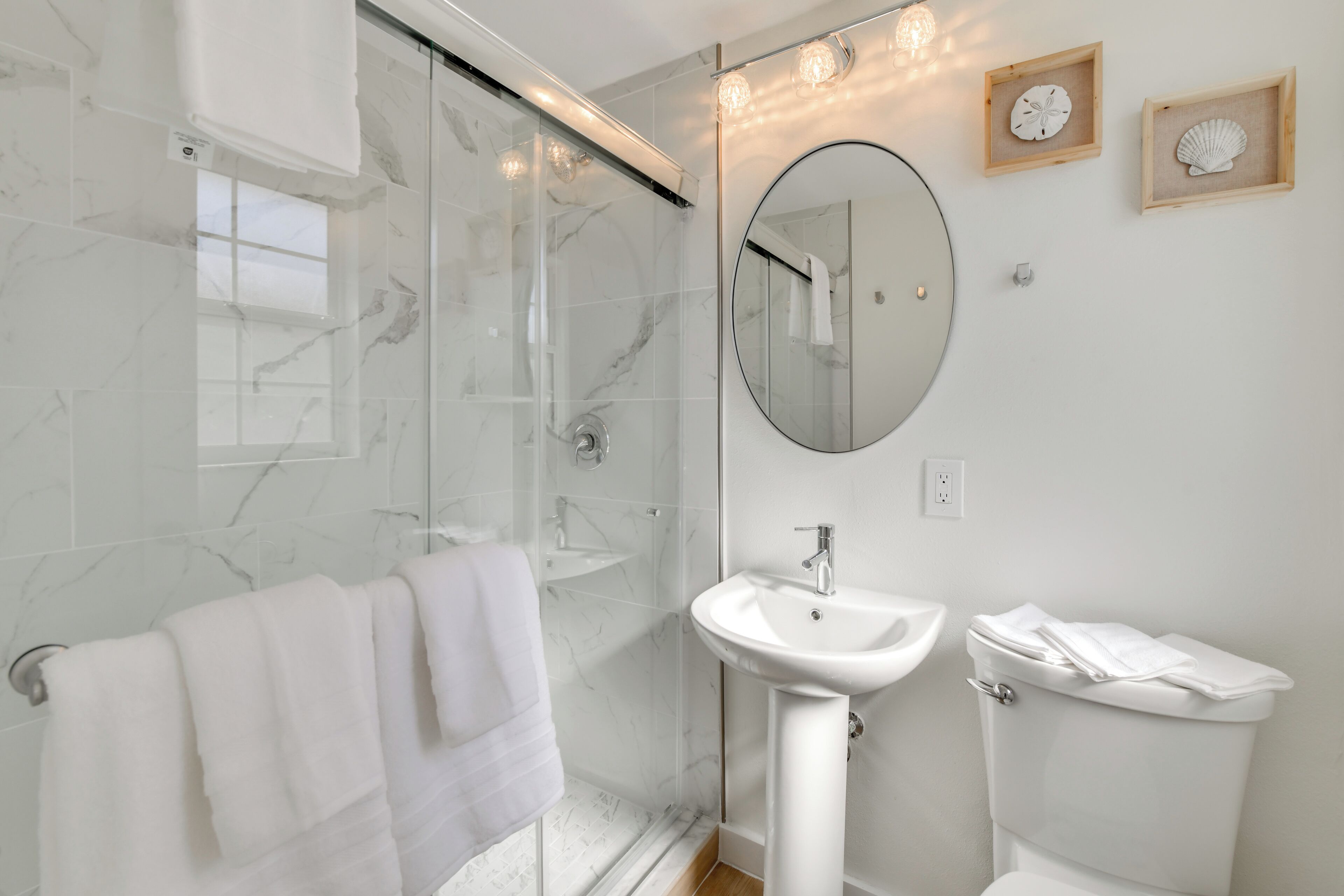 A modern bathroom with a glass shower enclosure, a white sink, and a toilet.