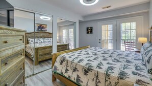 A bedroom with a wooden bed, a dresser, a mirror, and a door with windows. - 3BR Gatlinburg Retreat w/ Hot Tub & Balconies (Gatlinburg)