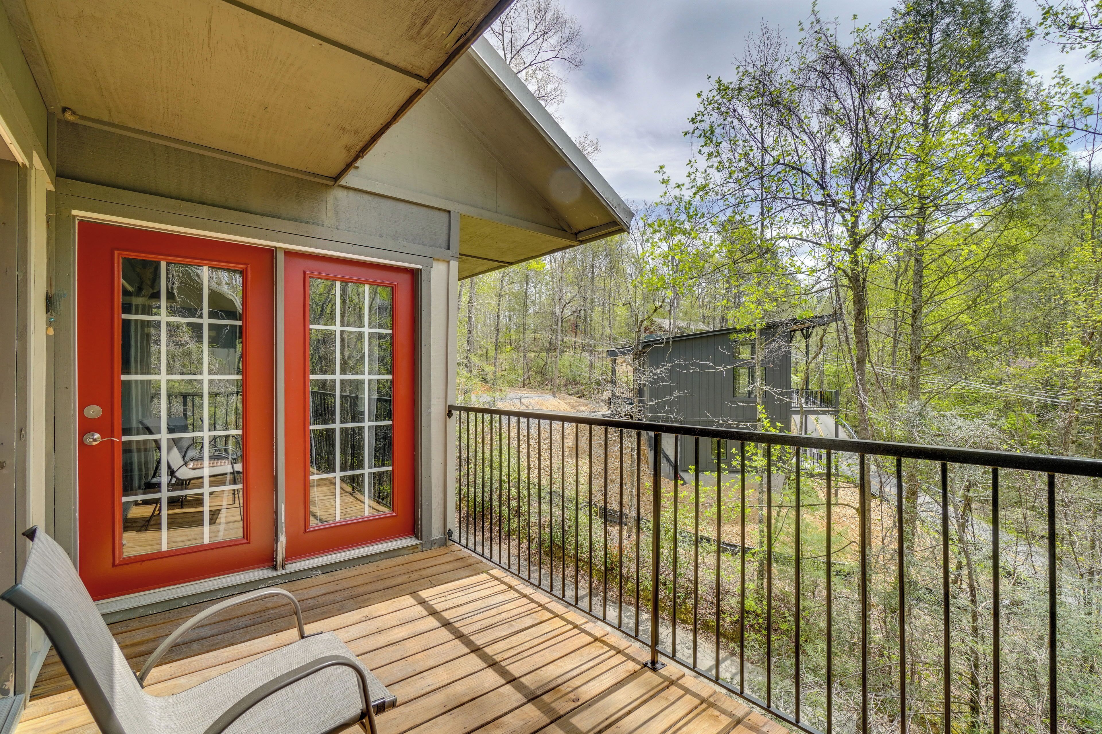 A wooden deck with a red door and a metal railing.