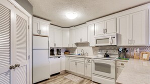 A kitchen with white cabinets, a microwave, an oven, and a sink.