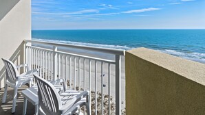 Ein Balkon mit weißen Stühlen mit Blick auf einen Strand.