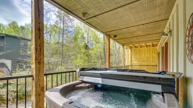 A hot tub on a wooden deck with a view of a forest. - Modern Gatlinburg Retreat w/ Private Hot Tub (Gatlinburg)
