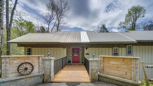 A lodge with a wooden ramp leading to a red door, a wheel on the left, and a sign on the right. - Modern Gatlinburg Retreat w/ Private Hot Tub (Gatlinburg)