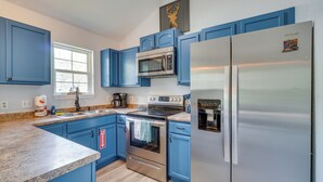 A kitchen with blue cabinets, stainless steel appliances, a microwave, oven, and a refrigerator. - Modern Gatlinburg Retreat w/ Private Hot Tub (Gatlinburg)