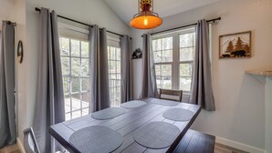 A dining area with a large table, grey curtains, and a hanging light fixture. - Modern Gatlinburg Retreat w/ Private Hot Tub (Gatlinburg)