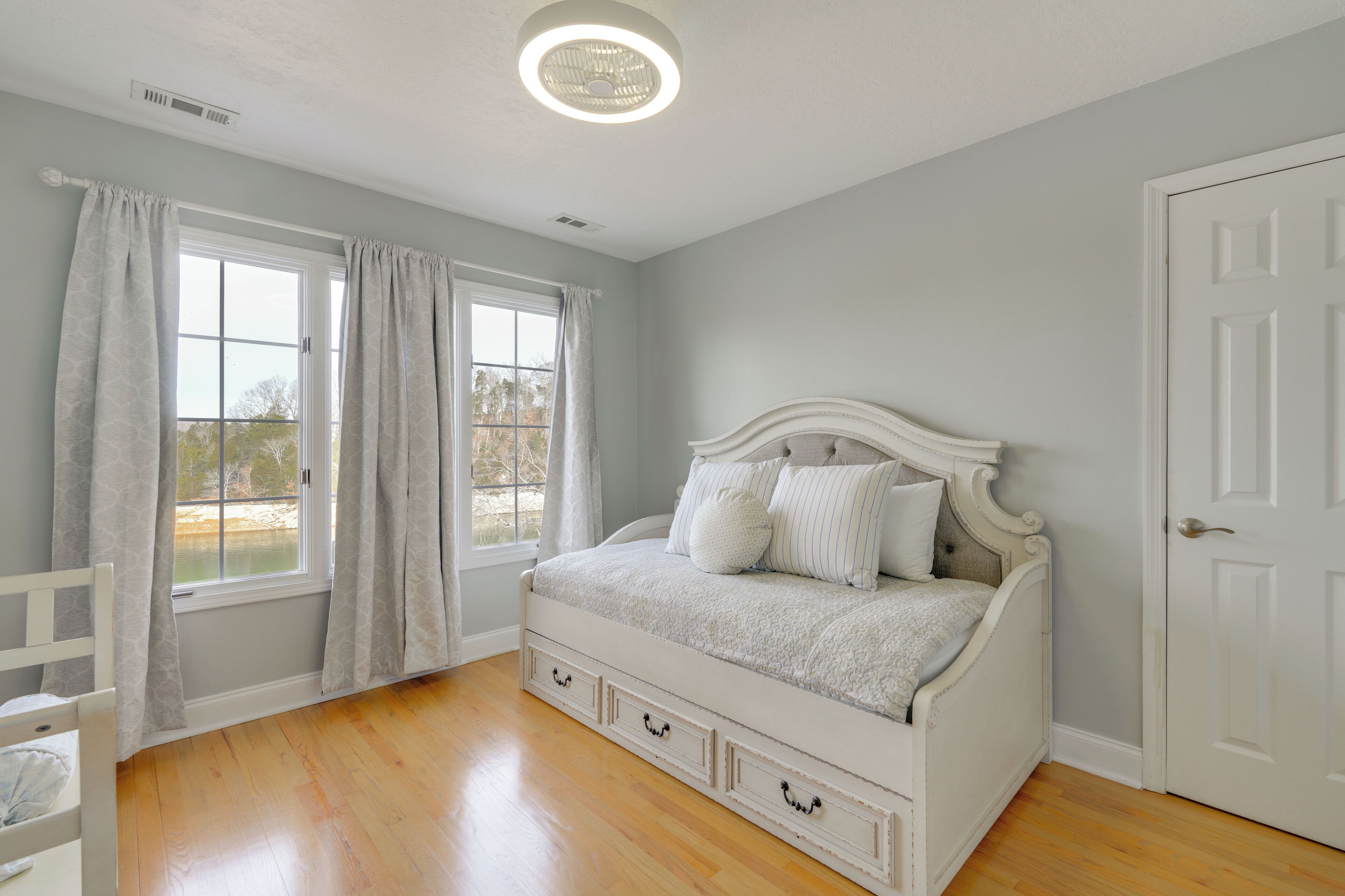 Una camera da letto con un letto bianco, una finestra con tende e una porta.