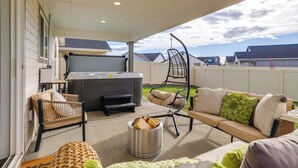 En overdækket terrasse med jacuzzi, siddepladser og bålsted.