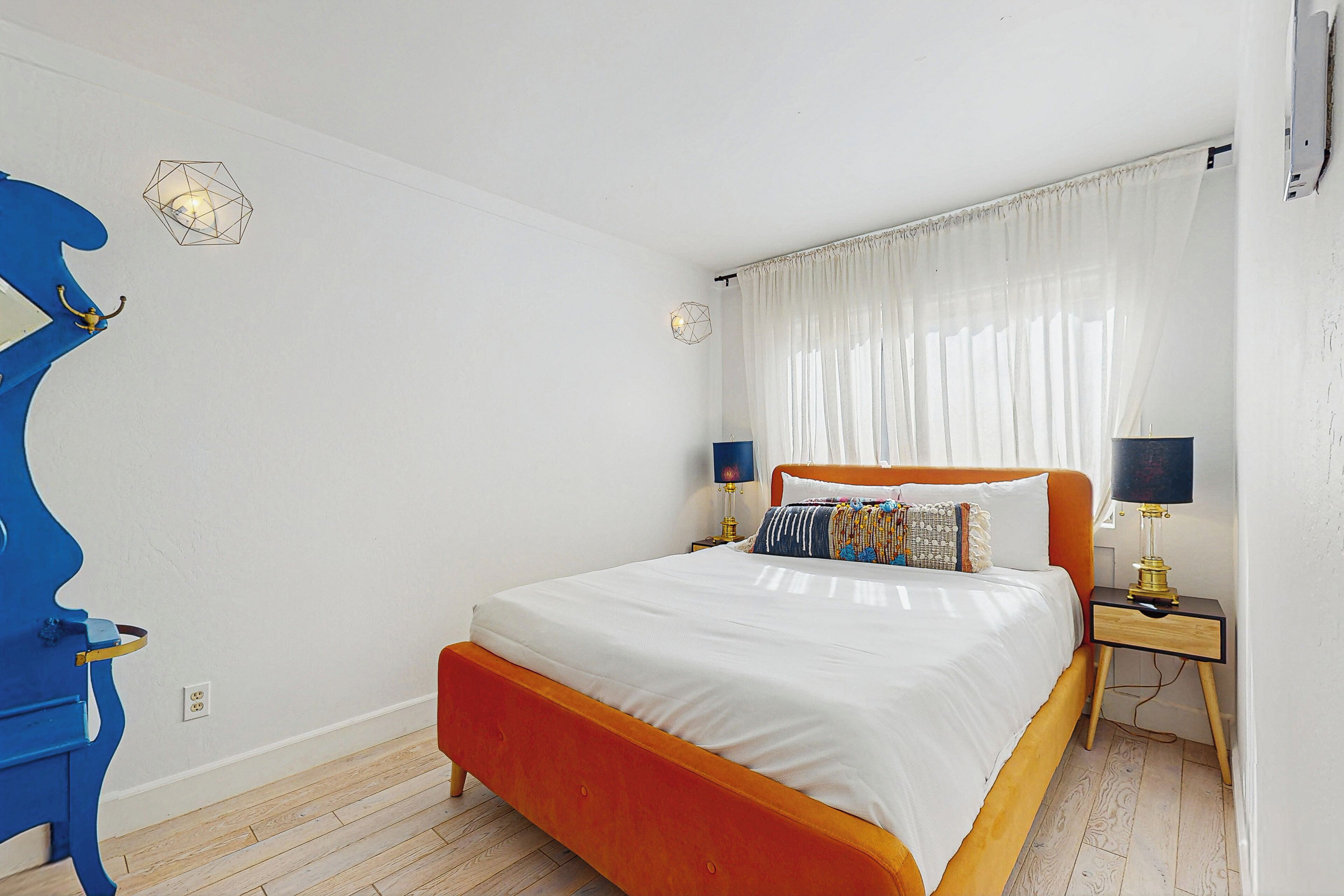 A bedroom with a bed, nightstands, and a unique blue chair.