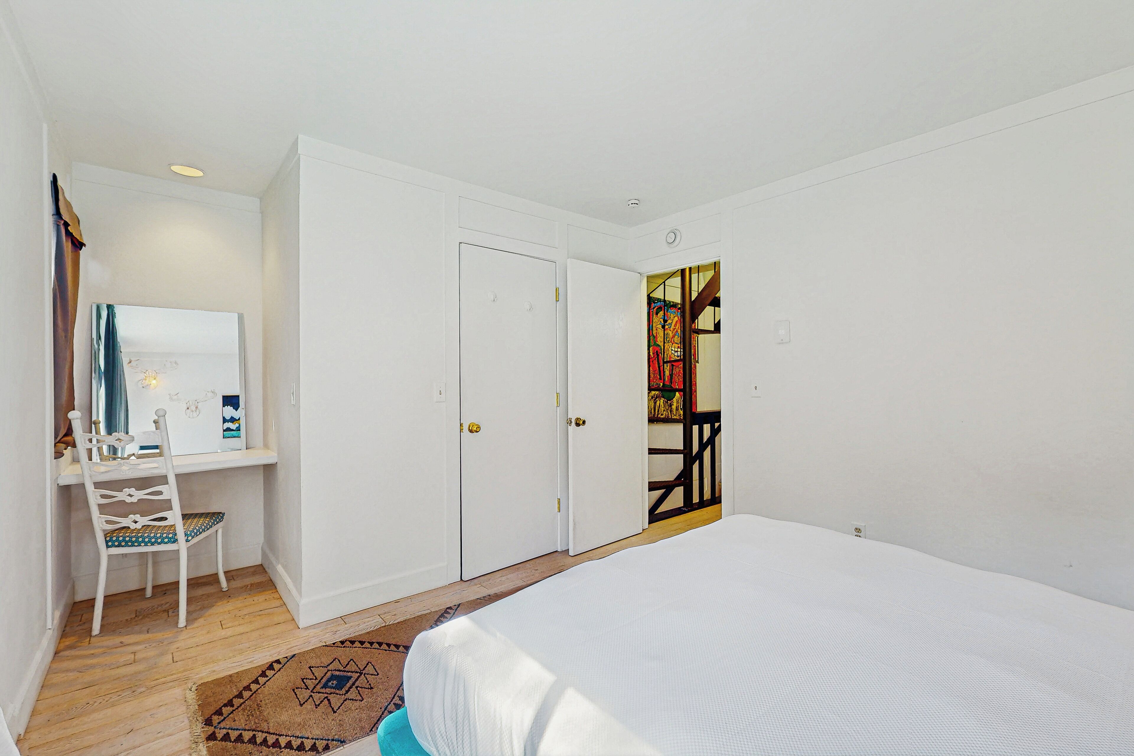 A bedroom with a bed, a desk with a chair, and a wardrobe.