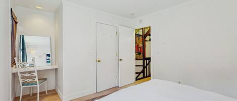 A bedroom with a bed, a desk with a chair, and a wardrobe.