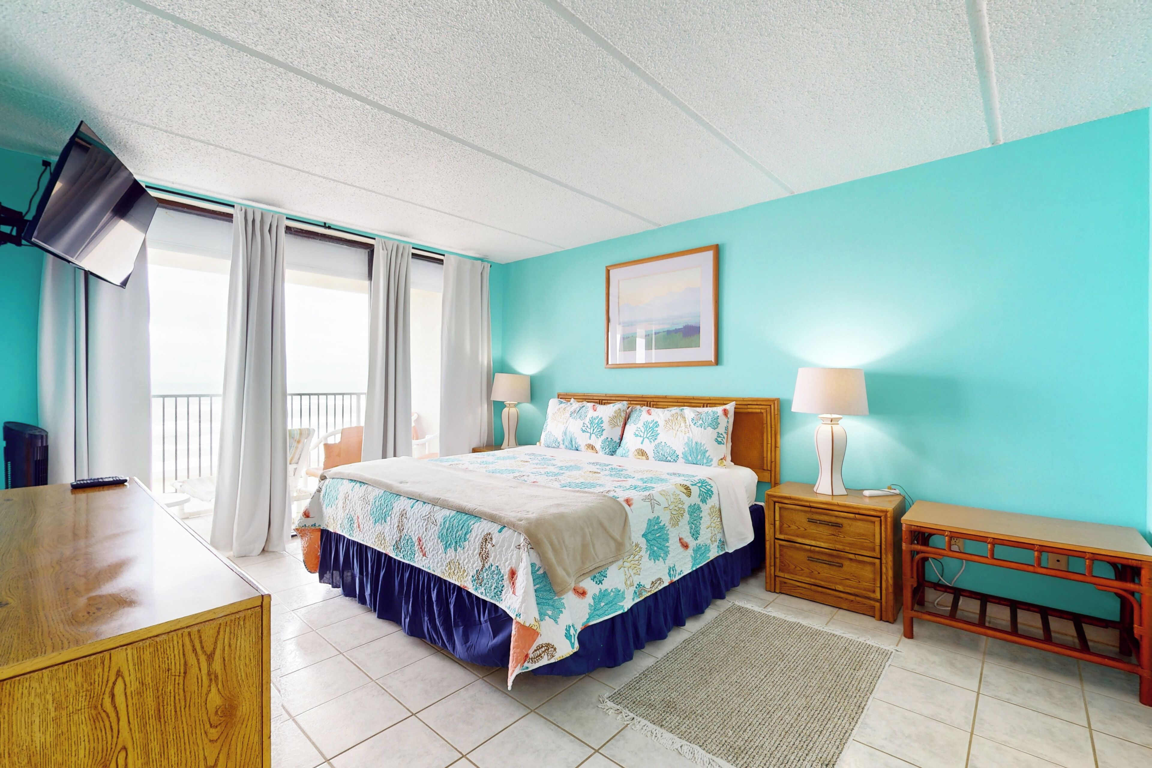 A bedroom with a bed, bedside tables, a desk, and a TV.