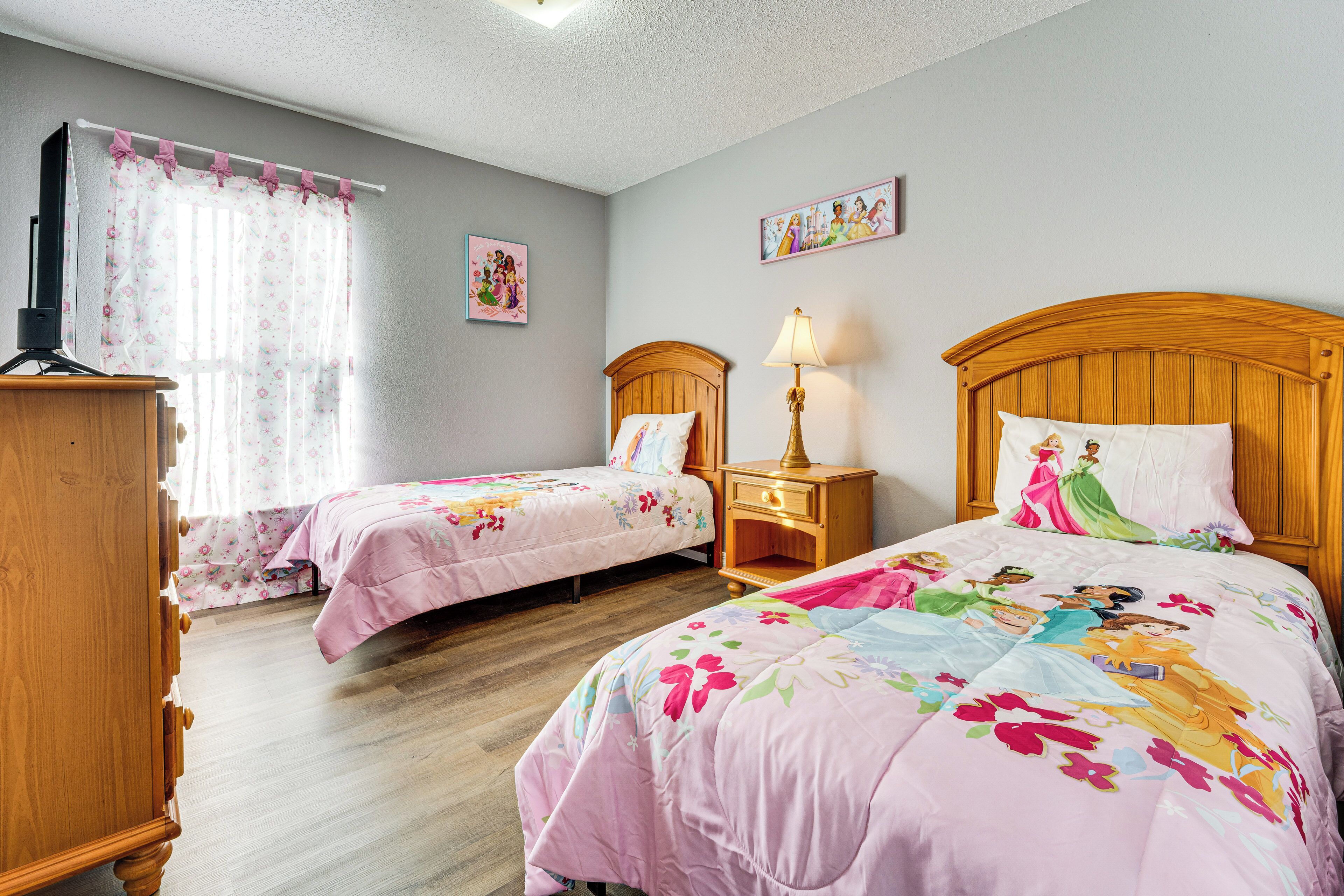 Un dormitorio con dos camas individuales, un armario de madera, una mesita de noche con lámpara y cortinas con estampado floral.