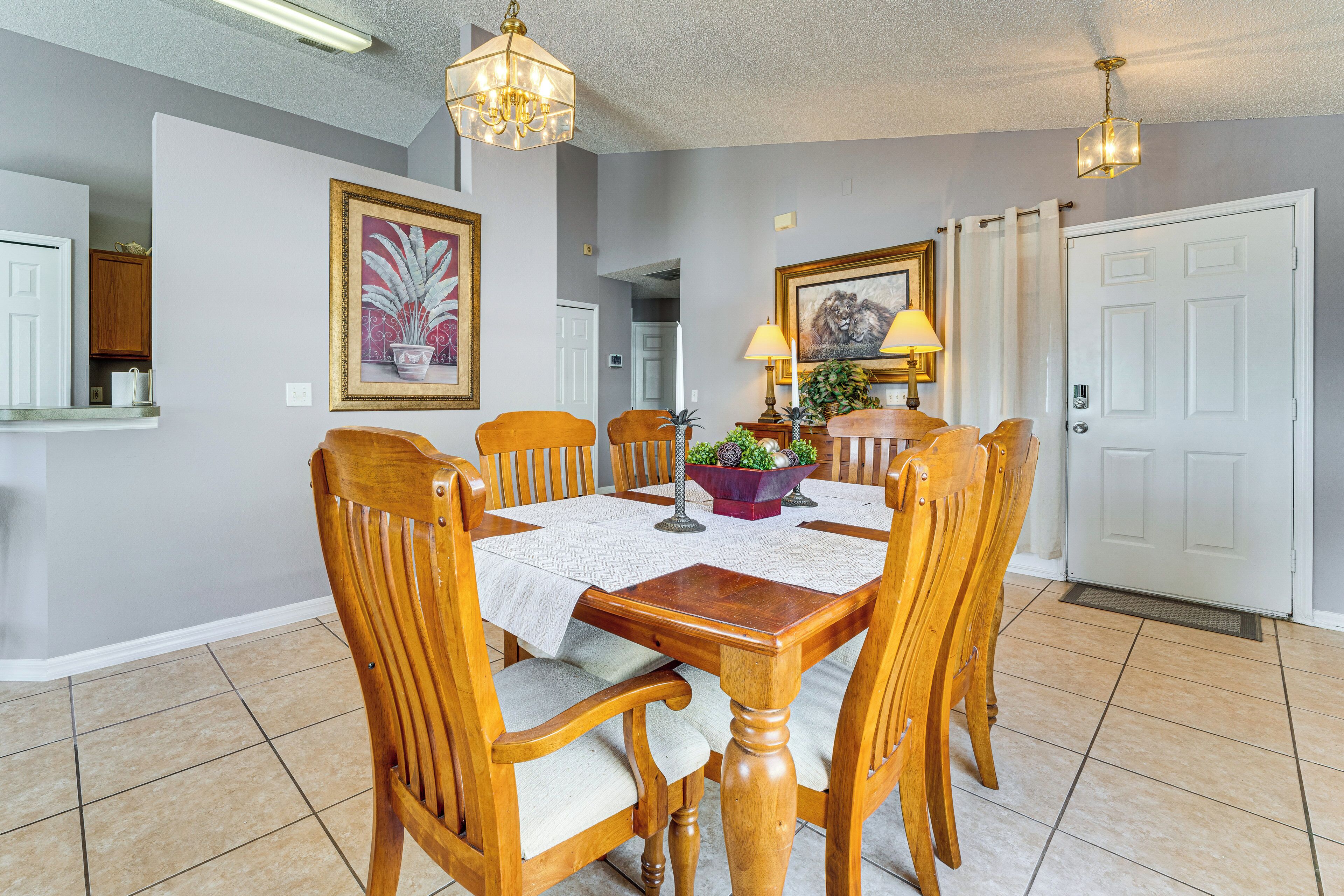 A dining room with a wooden table and chairs, a chandelier, and framed artwork on the walls.