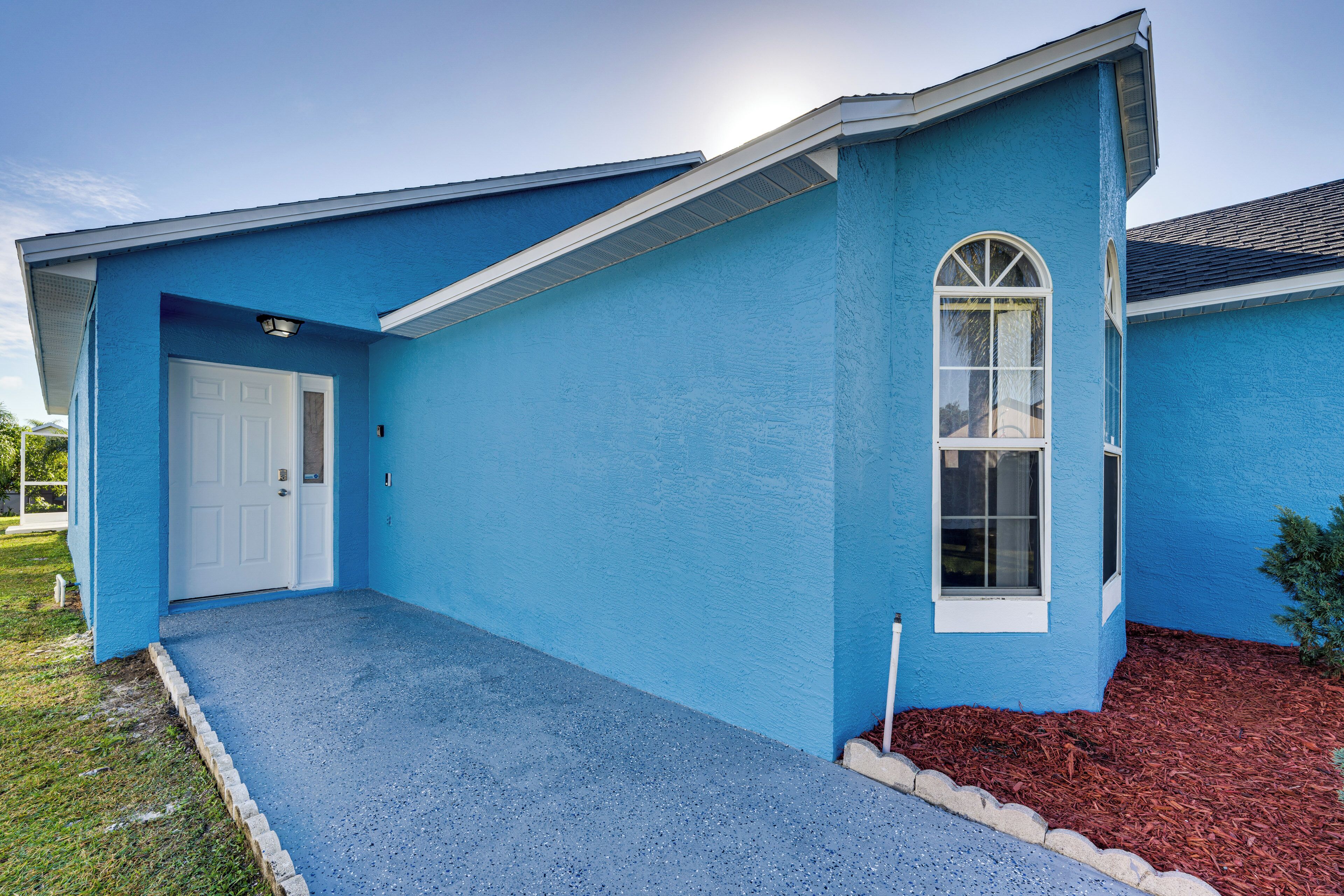 A blue house with a white door, a window, and a small porch area.