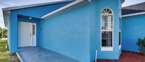 A blue house with a white door, a window, and a small porch area.