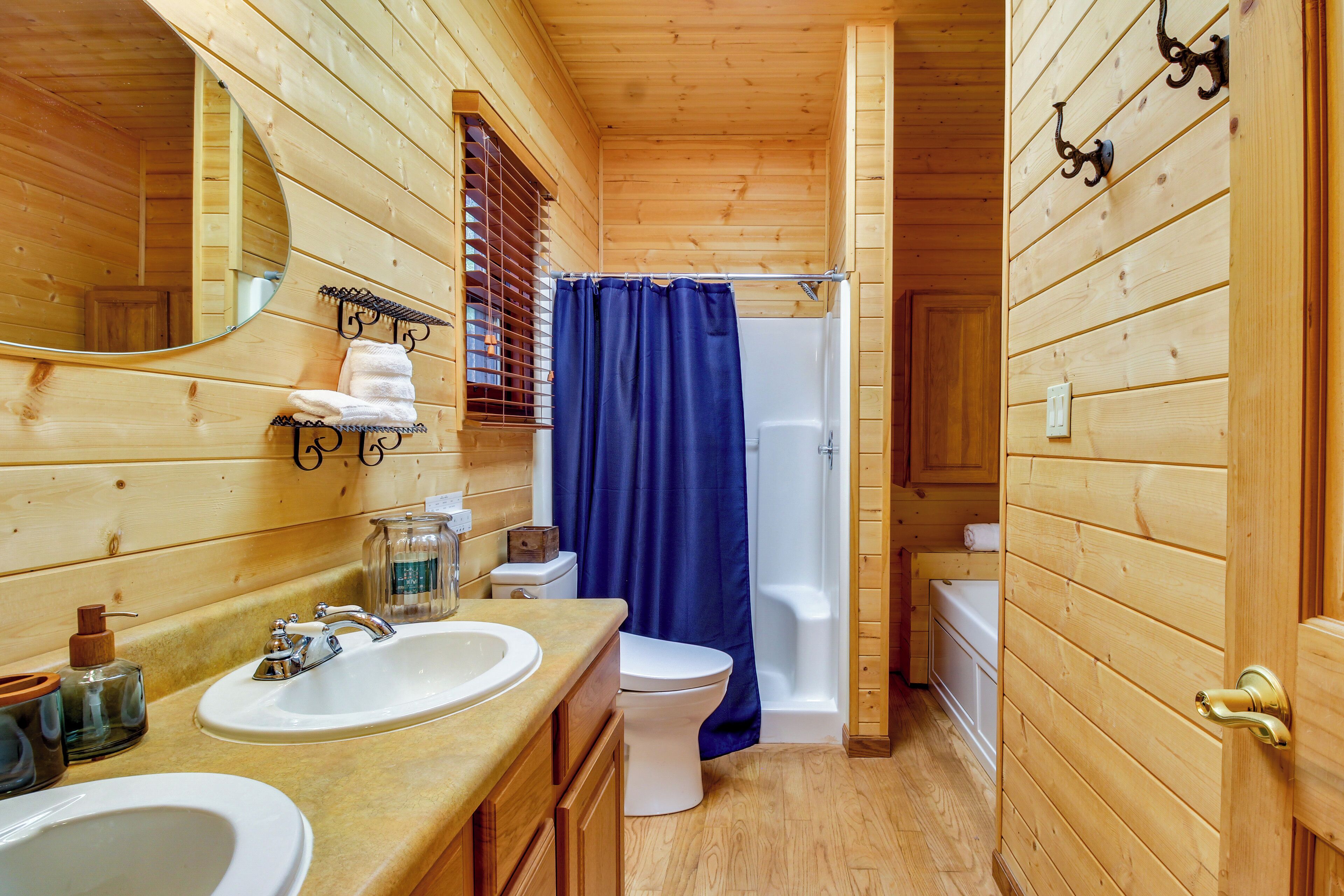 Ein Badezimmer einer Holzhütte mit zwei Waschbecken, einer Toilette, einer Dusche und einem Spiegel.