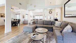 Ein geräumiges Wohnzimmer mit einer Eckcouch, zwei Couchtischen und einem Essbereich mit Tisch und Stühlen.
