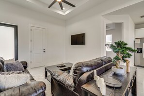 A modern living room with a dark leather sofa, a coffee table, and a potted bonsai tree. - Home Gym & Sauna! Luxe Lehigh Acres Family Home (Lehigh Acres)