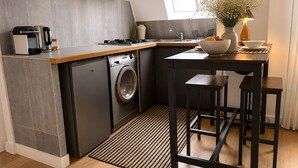 Una cocina compacta con lavadora, cafetera y zona de comedor con taburetes.