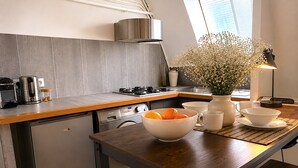 Una cocina moderna con encimera de madera, electrodomésticos de acero inoxidable y un florero con flores sobre la mesa.
