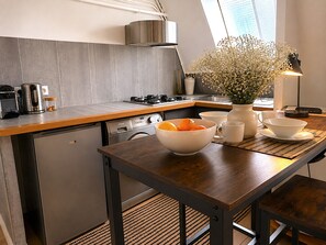 A modern kitchen with a wooden countertop, stainless steel appliances, and a vase with flowers on the table. - L'appartement Haudriettes (Paris03)