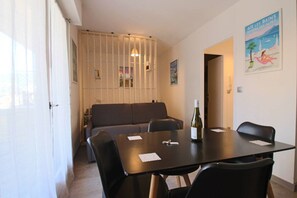 Uma área de refeições com mesa, cadeiras, um sofá e uma garrafa de vinho.