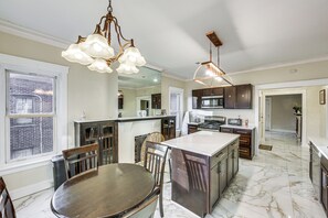 Una cocina moderna con suelo de mármol, mesa de comedor de madera e iluminación colgante.