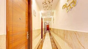 A hallway with a wooden door, marble flooring, and a decorative ceiling. - Roomshala Hotel Smart  (New Delhi)