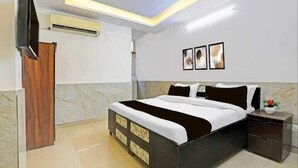 A modern bedroom with a bed, bedside tables, a TV, and artwork on the wall. - Roomshala Hotel Smart  (New Delhi)