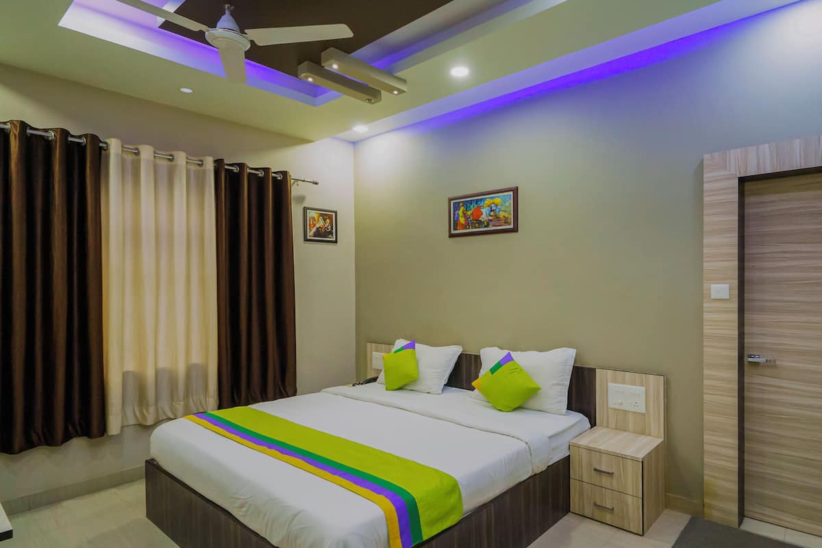Una habitación de hotel moderna con una cama grande, mesitas de noche, un ventilador de techo y una puerta con cerradura.