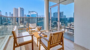 Un balcone con arredi in legno e ringhiera in vetro, con vista sulla città.