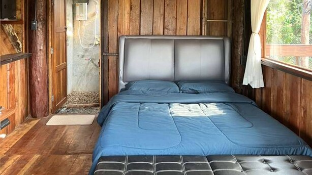 A wooden cabin bedroom with a bed, a window with curtains, and a shower area. - Room-boutique Cabin · Peaceful Mountain (Chiang Dao)