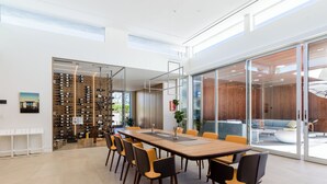 A modern meeting room with a long table, chairs, and a wine rack. - Above Palm Springs Sanctuary | Mountain Views | Pool & Spa | Old Las Palmas (Palm Springs)