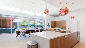 A modern kitchen with a large island, wooden cabinets, and pendant lighting. - Above Palm Springs Sanctuary | Mountain Views | Pool & Spa | Old Las Palmas (Palm Springs)