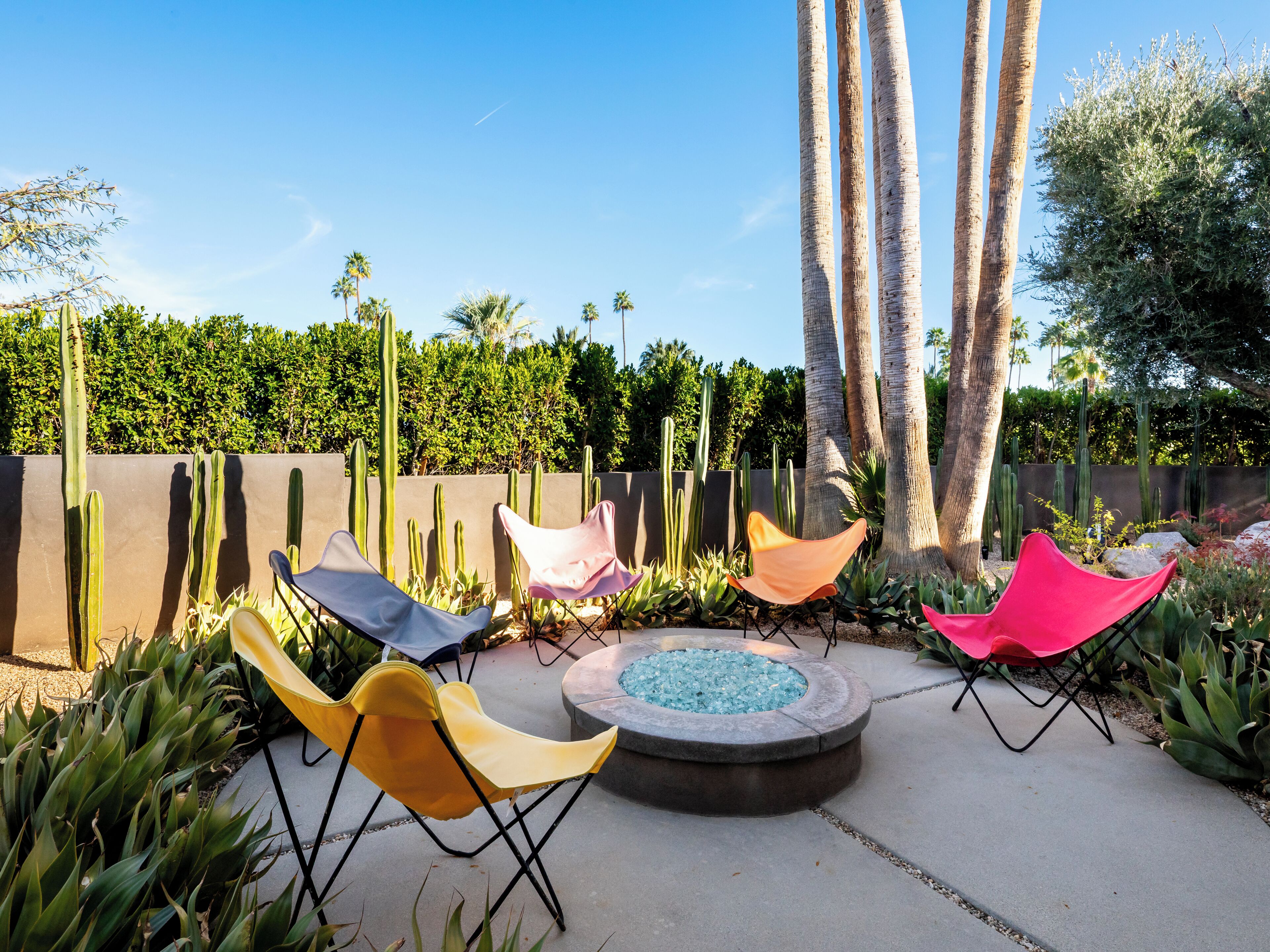 An outdoor seating area with colorful chairs and a circular stone fire pit.