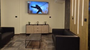 Ein modernes Wohnzimmer mit Fernseher, zwei Sofas, einem Couchtisch und einer Holzkommode mit Dekorationen.