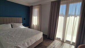 Ein Hotelzimmer mit Bett, Vorhängen und Blick ins Freie.