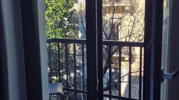 Ein Zimmer mit einer großen Schiebeglastür, die auf einen Balkon mit Metallgeländer im Freien führt.