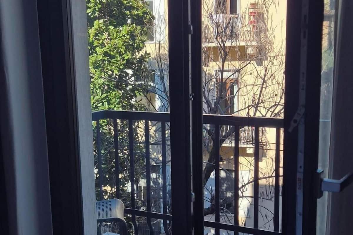 A room with a large sliding glass door leading to an outdoor balcony with a metal railing.