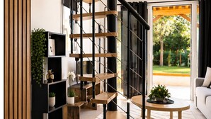 Un soggiorno moderno con una scala a chiocciola, un divano, un tavolino da caffè e una libreria con piante.